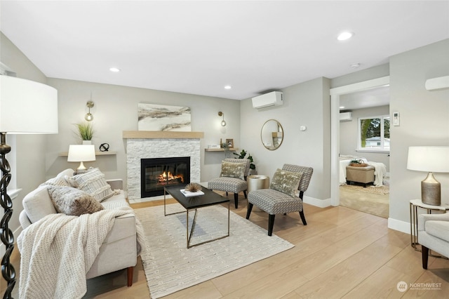 living room with a stone fireplace, light hardwood / wood-style floors, and an AC wall unit