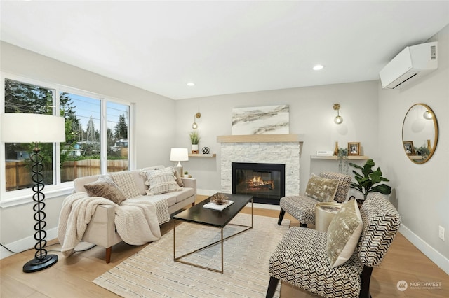 living room featuring a fireplace, a wall unit AC, and light hardwood / wood-style flooring