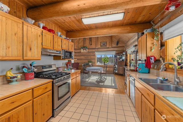 kitchen with rustic walls, sink, light tile patterned floors, tile counters, and stainless steel appliances