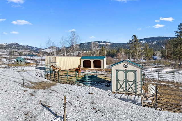 yard covered in snow with a mountain view and a storage unit