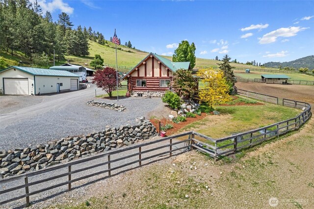 1427 N Chapin Rd, Evans, WA 99126 - view of front of house featuring a garage, a rural view, gravel driveway, an outbuilding, and log siding