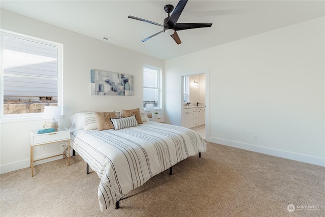 bedroom with light colored carpet, ceiling fan, and ensuite bath