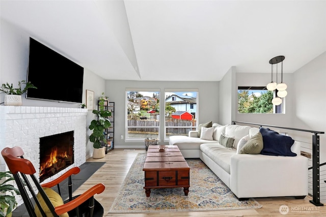 living area with a brick fireplace, light wood-style flooring, and baseboards