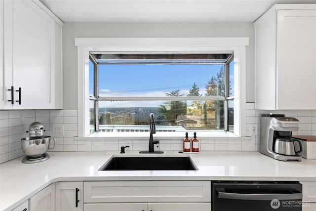 kitchen featuring black dishwasher, light countertops, a sink, and white cabinets