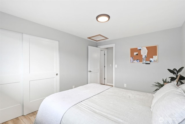 bedroom featuring a closet, attic access, and light wood-style floors