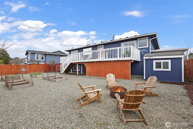 back of house featuring an outbuilding, a deck, a fire pit, a garden, and a shed