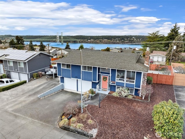 view of front facade featuring a water view, driveway, an attached garage, and roof with shingles