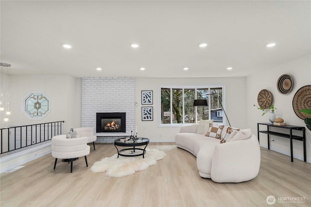 living room featuring light wood-style floors, a brick fireplace, baseboards, and recessed lighting