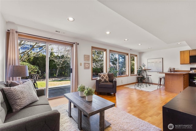 living room featuring light wood finished floors, baseboards, visible vents, and recessed lighting