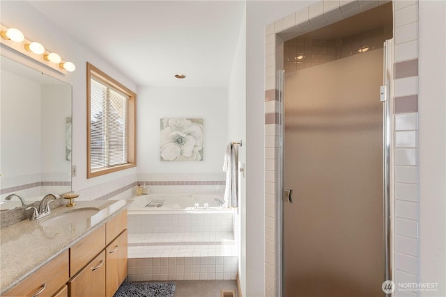 bathroom with a garden tub, a stall shower, and vanity