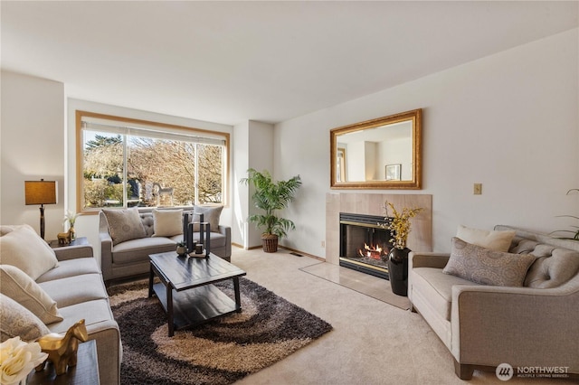 living room featuring light carpet, a tiled fireplace, and baseboards