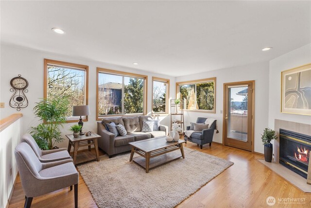 living area with light wood finished floors, a tile fireplace, and recessed lighting