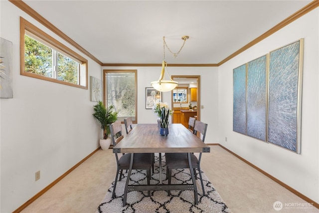 dining room featuring baseboards, ornamental molding, and light colored carpet