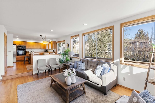 living area featuring baseboards, light wood-type flooring, and recessed lighting