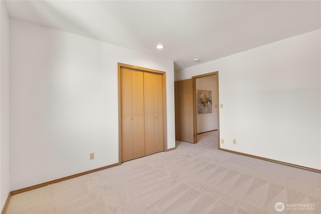 unfurnished bedroom featuring recessed lighting, a closet, light colored carpet, and baseboards