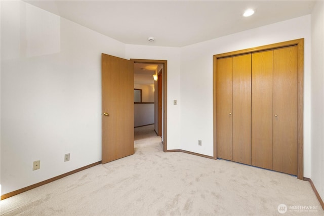 unfurnished bedroom featuring baseboards, a closet, and light colored carpet