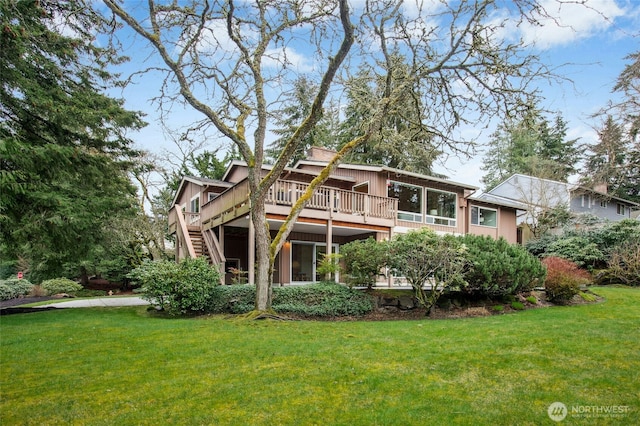 back of property with a deck, stairs, and a yard