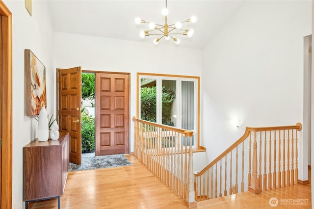 foyer entrance featuring vaulted ceiling, wood finished floors, and a chandelier