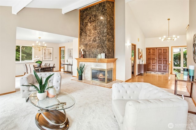 carpeted living area featuring baseboards, high vaulted ceiling, a high end fireplace, beamed ceiling, and a notable chandelier