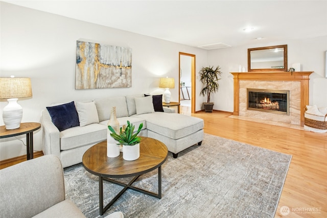 living area with baseboards, wood finished floors, and a tile fireplace