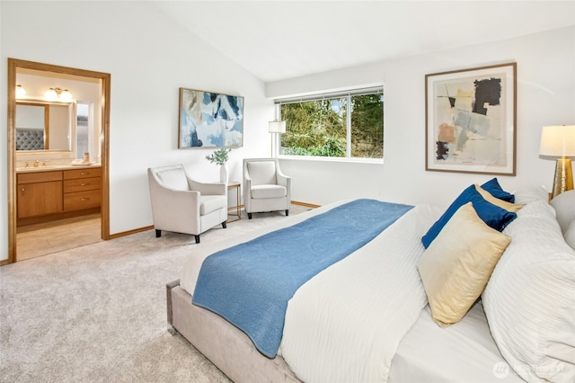 bedroom with baseboards, ensuite bath, lofted ceiling, a sink, and light colored carpet