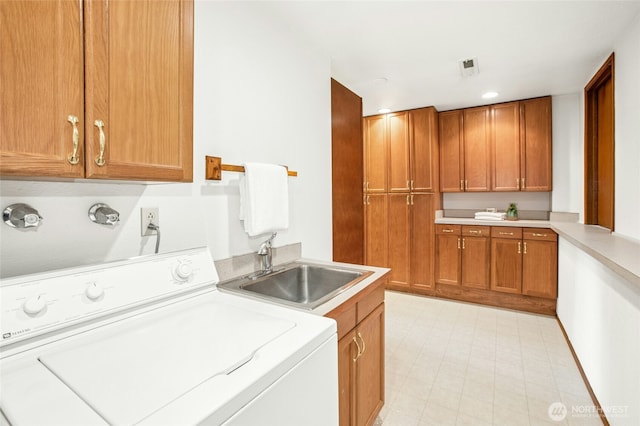 laundry area featuring light floors, visible vents, washer / dryer, cabinet space, and a sink