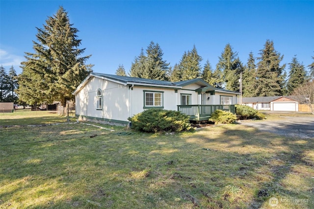 view of front of house with a wooden deck, a garage, and a front lawn