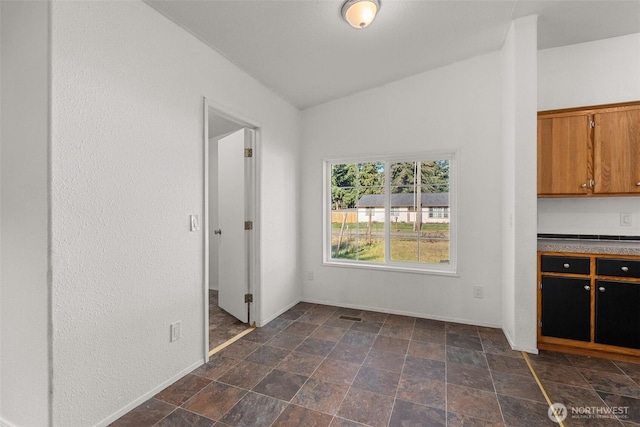 unfurnished dining area with vaulted ceiling