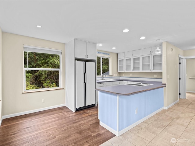 kitchen with white cabinetry, light hardwood / wood-style flooring, white appliances, and kitchen peninsula