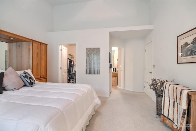 bedroom featuring light carpet, a walk in closet, a closet, and a high ceiling