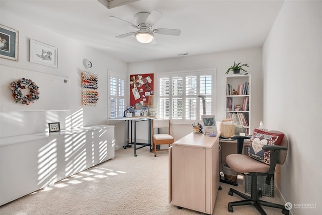 carpeted home office featuring ceiling fan