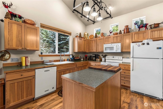 kitchen featuring vaulted ceiling, sink, a center island, dark wood-type flooring, and white appliances