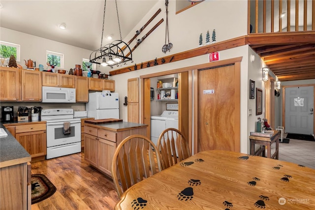 kitchen featuring white appliances, hanging light fixtures, high vaulted ceiling, separate washer and dryer, and light wood-type flooring