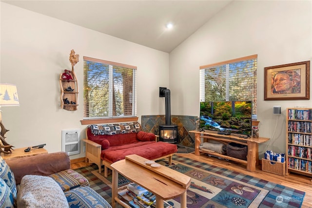 living room featuring hardwood / wood-style flooring, lofted ceiling, a wood stove, and heating unit