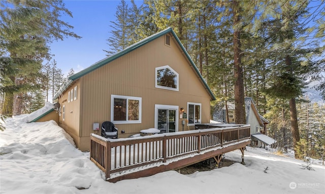 snow covered back of property featuring a wooden deck