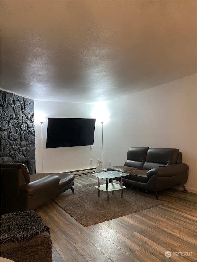 living room with hardwood / wood-style floors, a textured ceiling, and a baseboard heating unit