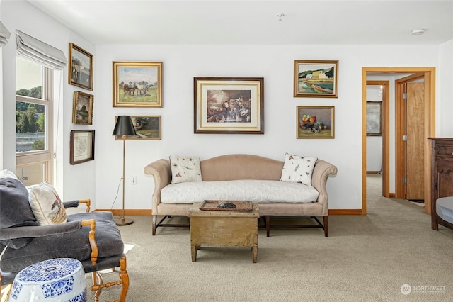 living area with baseboards and light colored carpet