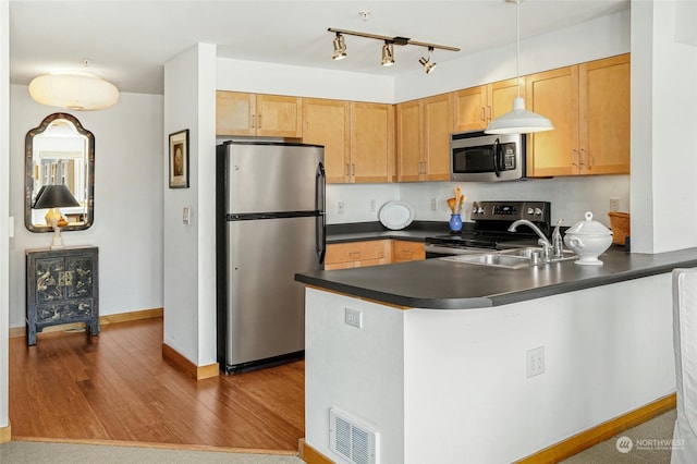 kitchen featuring stainless steel appliances, dark wood-type flooring, a peninsula, visible vents, and dark countertops