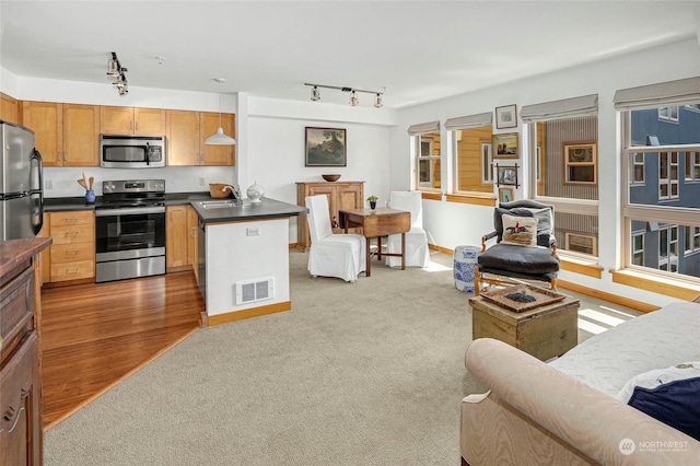 kitchen with stainless steel appliances, visible vents, open floor plan, brown cabinets, and dark countertops