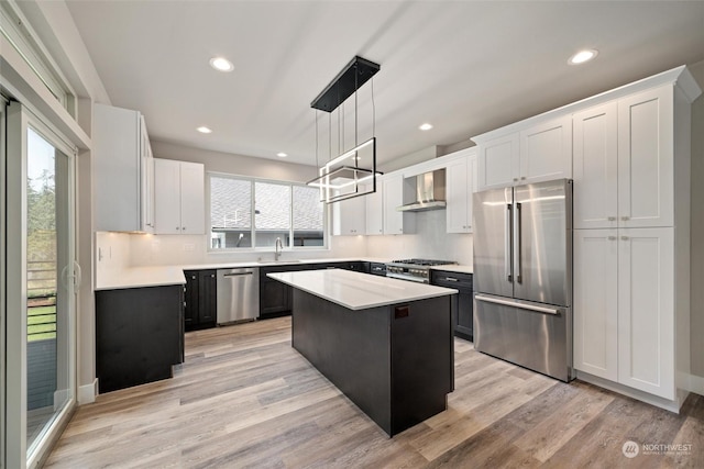 kitchen featuring white cabinets, wall chimney range hood, a kitchen island, and premium appliances