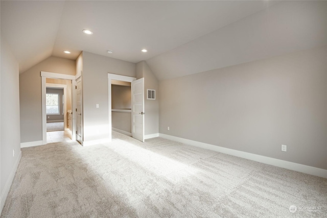 bonus room with lofted ceiling and light carpet