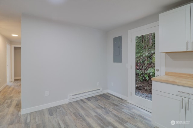 unfurnished dining area featuring electric panel, baseboard heating, and light hardwood / wood-style flooring