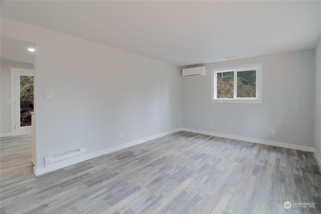 empty room with a wall mounted air conditioner and light hardwood / wood-style floors