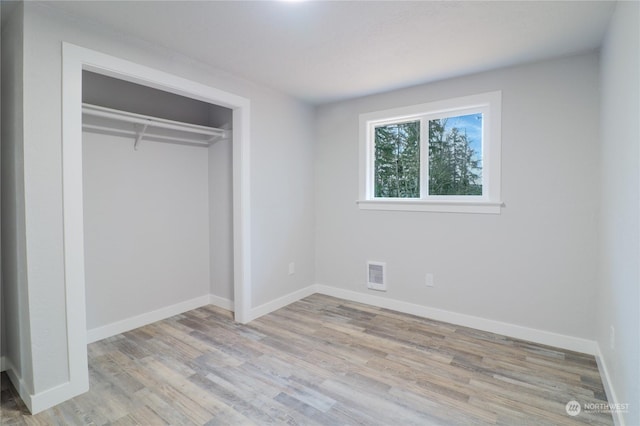 unfurnished bedroom with light wood-type flooring and a closet