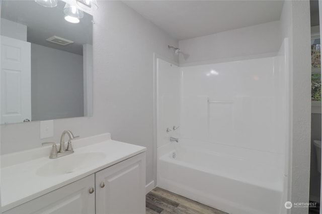 bathroom with vanity, hardwood / wood-style floors, and shower / washtub combination