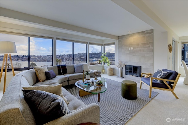 living room with a tiled fireplace, carpet flooring, and beamed ceiling