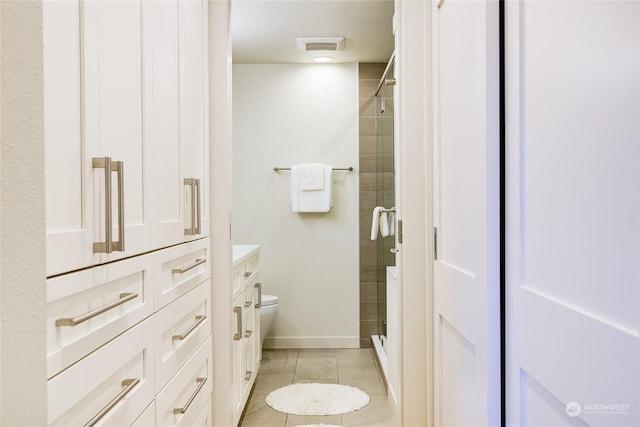 bathroom featuring tile patterned flooring, vanity, an enclosed shower, and toilet