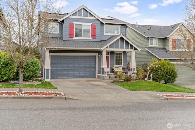 craftsman inspired home featuring a front lawn, roof with shingles, concrete driveway, a garage, and solar panels