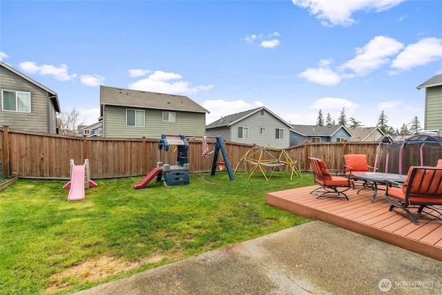 view of yard featuring a playground, a trampoline, a fenced backyard, and a wooden deck