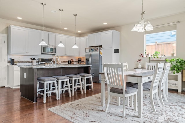 dining area featuring dark wood-type flooring, a notable chandelier, and recessed lighting